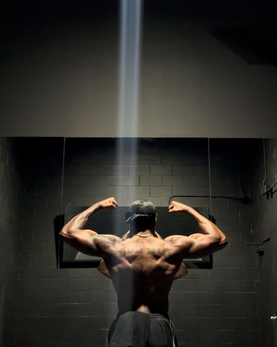 A back pose under a beam of light in a dark gym